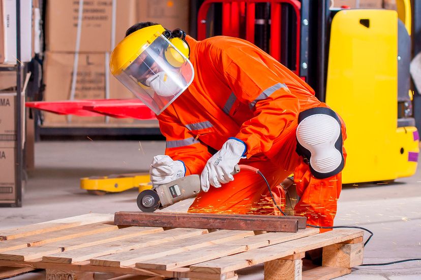 Trabajador con equipo de protección cortando metal en un almacén