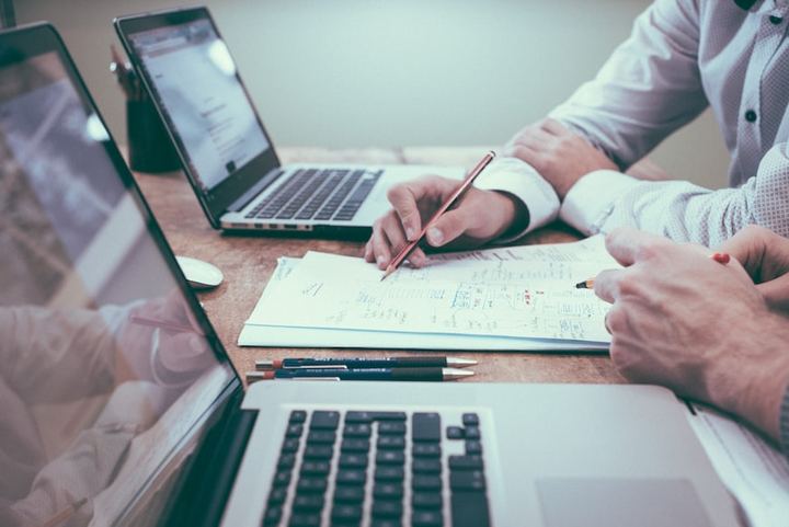 Profesionales revisando documentos junto a ordenadores portátiles